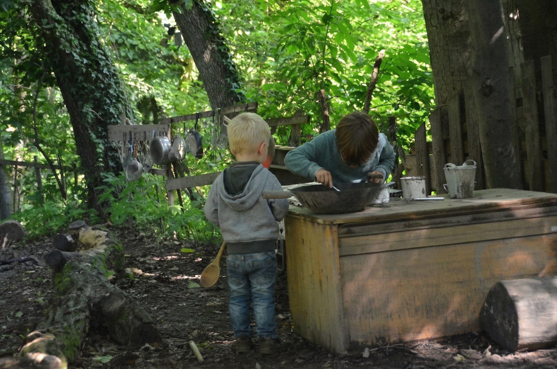 Kinder sitzen und klettern auf einem großen Baumstamm im Wald